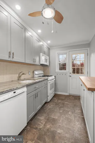 a large white kitchen with a large window stainless steel appliances and cabinets