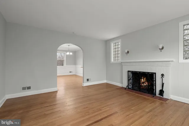 a view of an empty room with wooden floor fireplace and a window