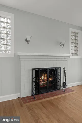 a view of an empty room with wooden floor and a fireplace
