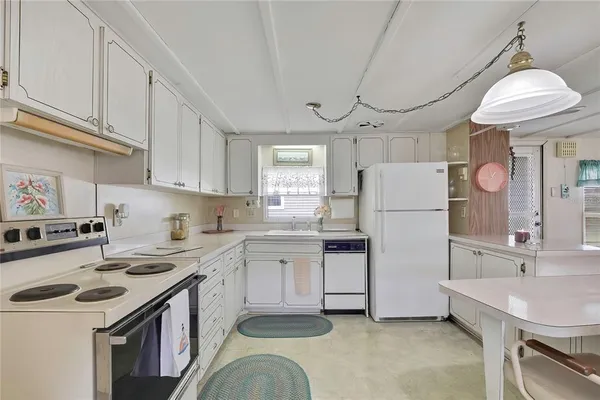 a kitchen with a sink a stove a refrigerator and white cabinets