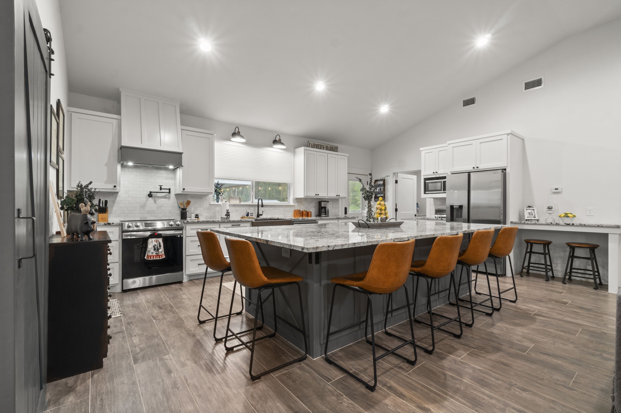 15651 Ben Wiggins Road Conroe, TX 77303 - Photo 11 of 47 a kitchen with stainless steel appliances kitchen island granite countertop a table chairs sink and cabinets