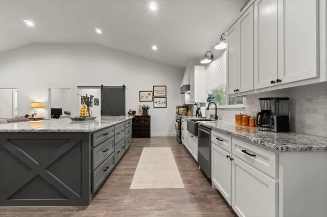 a large kitchen with stainless steel appliances kitchen island granite countertop a large counter top and a stove top oven