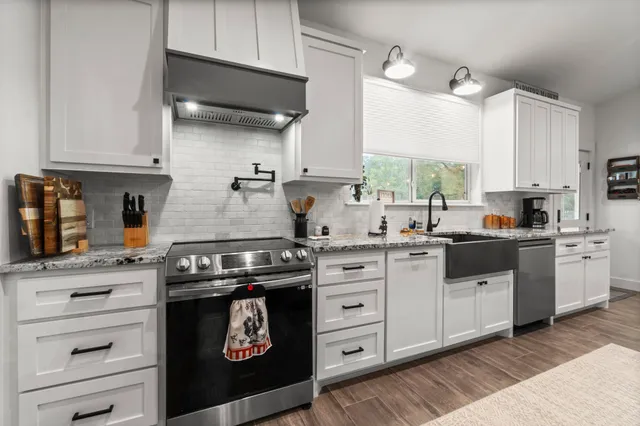 a kitchen with granite countertop a stove sink and cabinets
