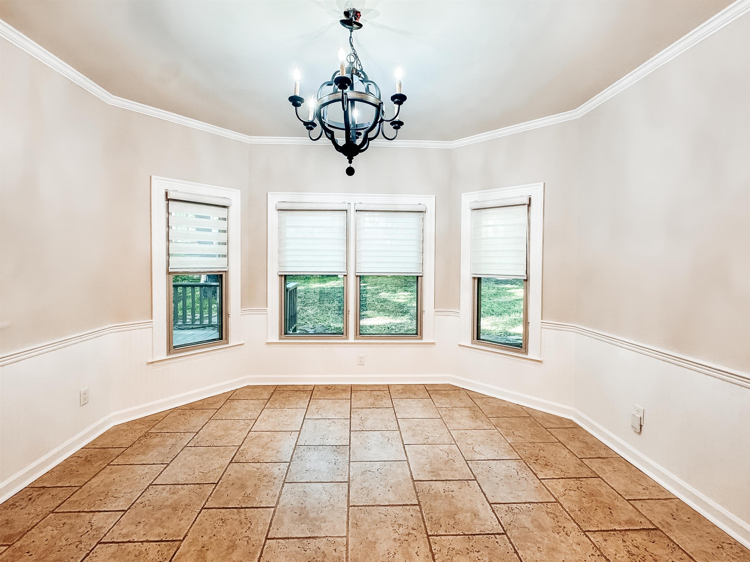 832 South Tree Drive Collierville, TN 38017 - Photo 10 of 40 Dining area featuring ceramic tile flooring, three large windows, white wainscoting, crown molding, and a chandelier