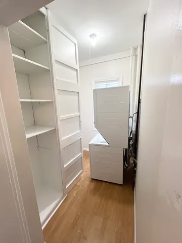 a view of an empty room with wooden floor and windows