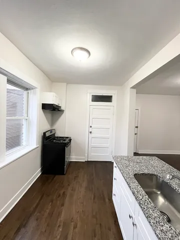 a kitchen with granite countertop a sink and a stove top oven