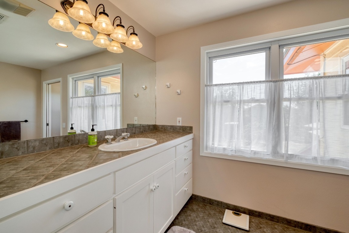 7600 Deer Run Road Leander, TX 78641 - Photo 19 of 39 a bathroom with a granite countertop sink and a window