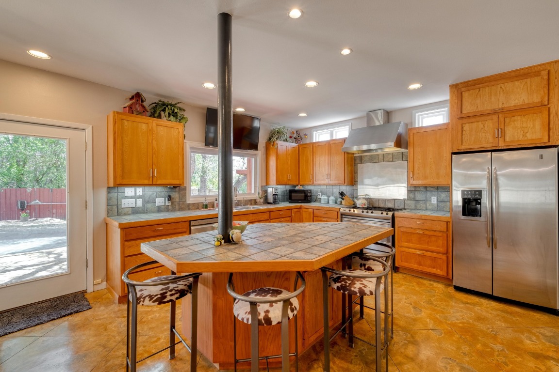 7600 Deer Run Road Leander, TX 78641 - Photo 10 of 39 a kitchen with stainless steel appliances granite countertop a kitchen island a stove a dining table and chairs with wooden floor