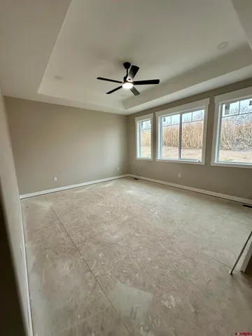 an empty room with windows and ceiling fan