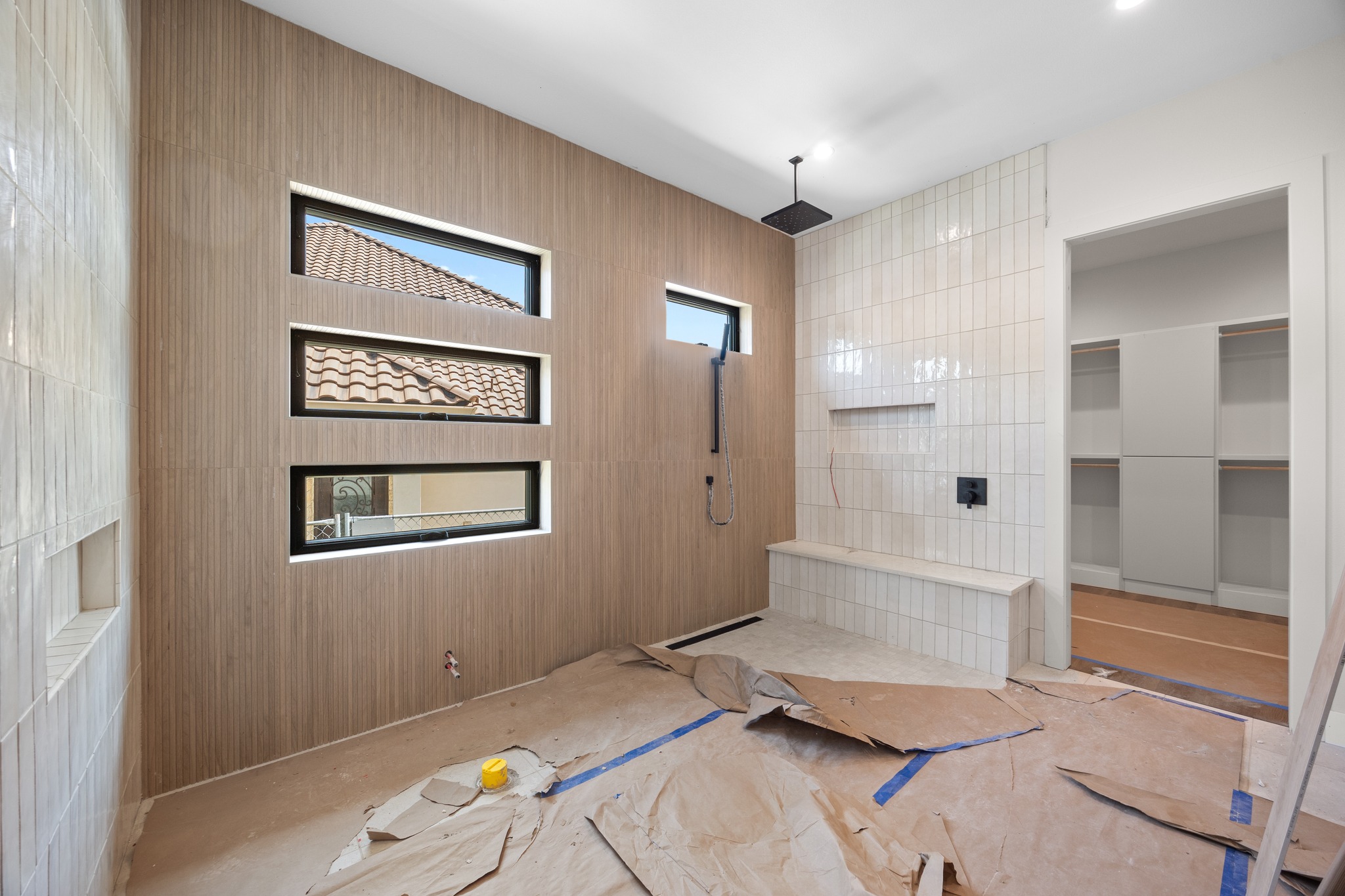 903 Flint Ridge Trail Georgetown, TX 78628 - Photo 23 of 39 Spacious shower area featuring light wood-finish wall paneling, three horizontal windows with black framing, and a tiled shower wall with a built-in bench and recessed niche