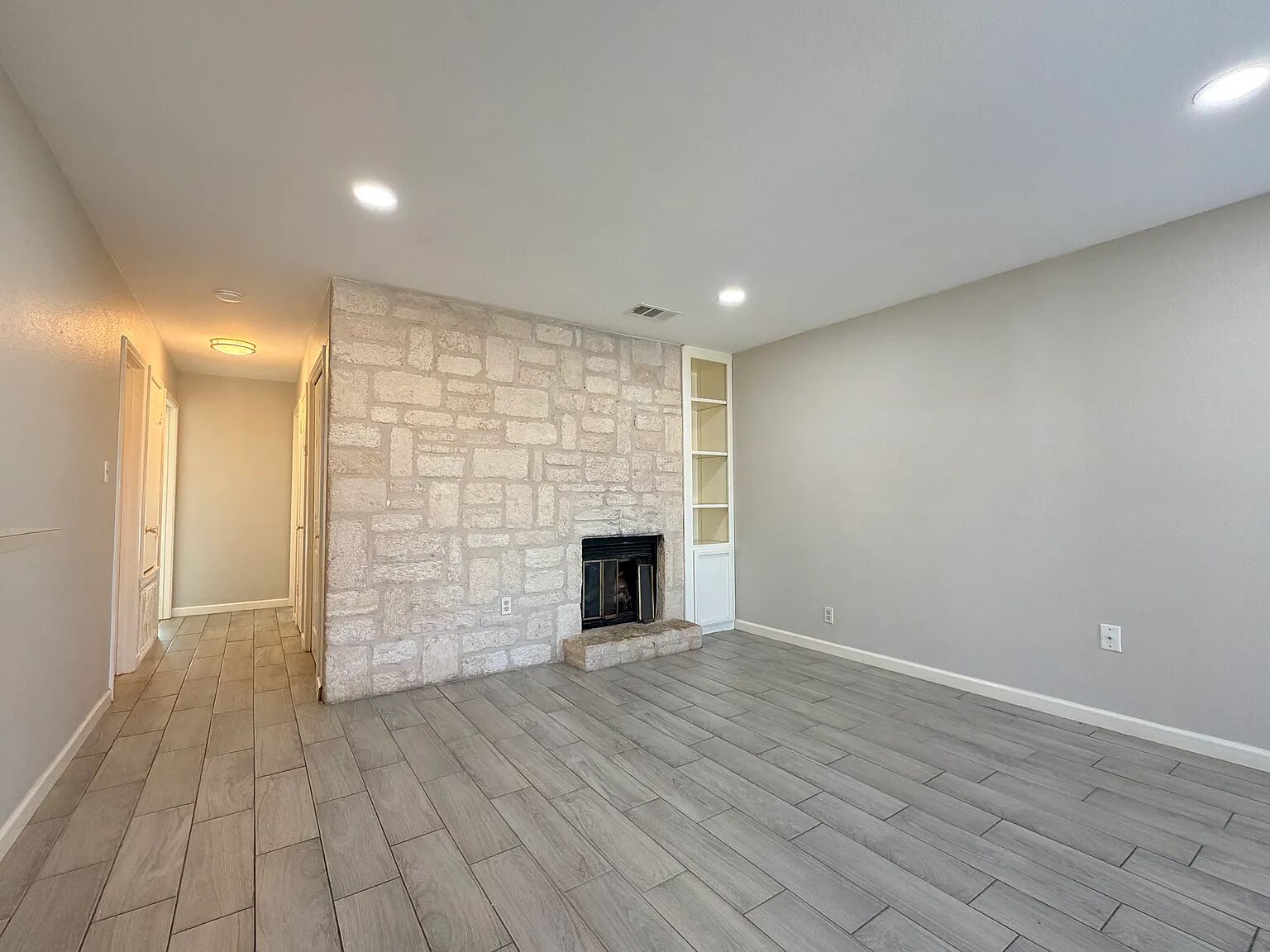 209 East Noton Street, Unit 109 Pflugerville, TX 78660 - Photo 3 of 11 an empty room with wooden floor and fireplace