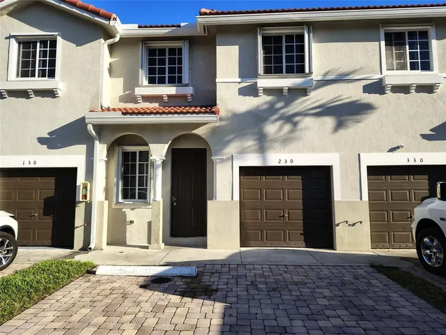 a view of a house with a barbeque and large trees