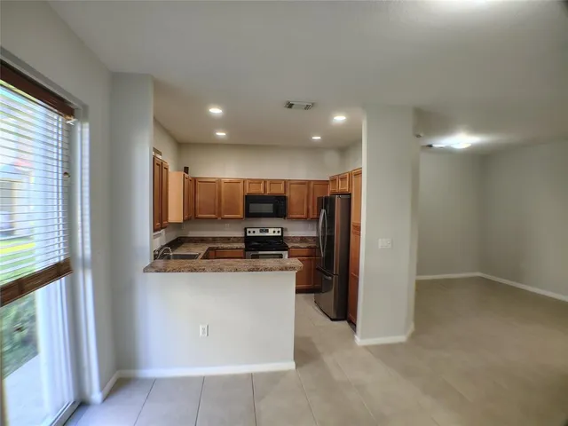 a kitchen with stainless steel appliances granite countertop a refrigerator a stove and a sink