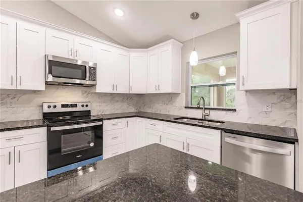 a kitchen with stainless steel appliances granite countertop a sink stove and microwave
