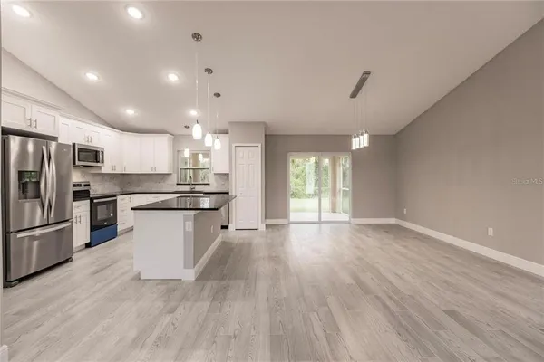 a kitchen with stainless steel appliances kitchen island a refrigerator a sink dishwasher and a stove with wooden floor