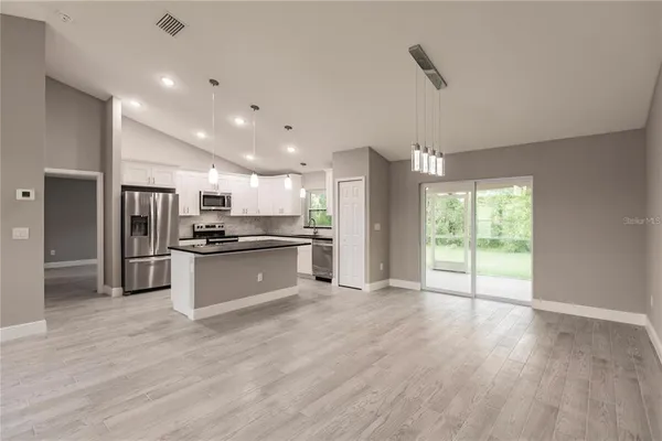 a large kitchen with stainless steel appliances kitchen island a large counter top and wooden floors