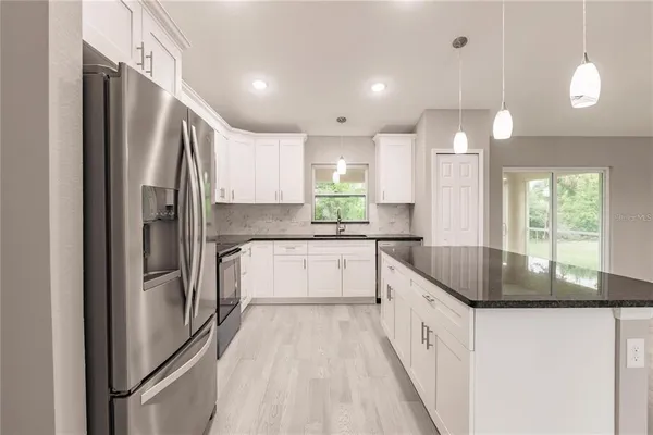 a kitchen with stainless steel appliances granite countertop a refrigerator a sink and a stove