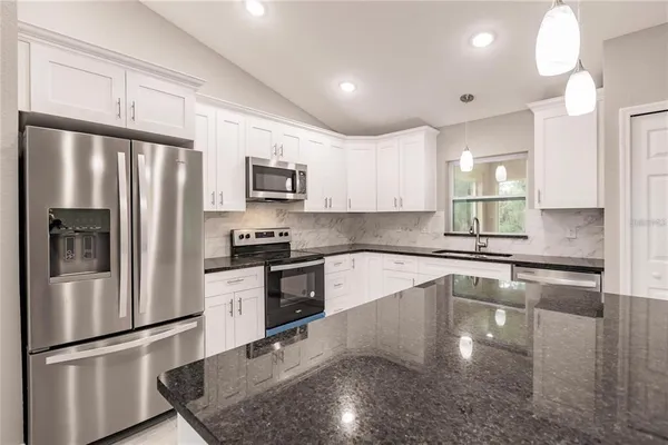 a kitchen with granite countertop a refrigerator and a sink
