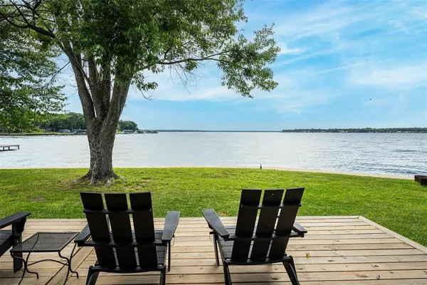 a view of a chairs and table on the deck near a yard