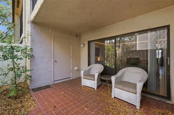 a balcony with couple of chairs and a potted plant