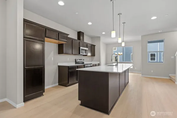 a large kitchen with stainless steel appliances kitchen island granite countertop a stove a sink and a microwave