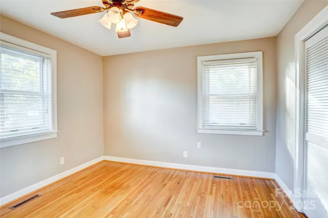 a view of an empty room with window and wooden floor