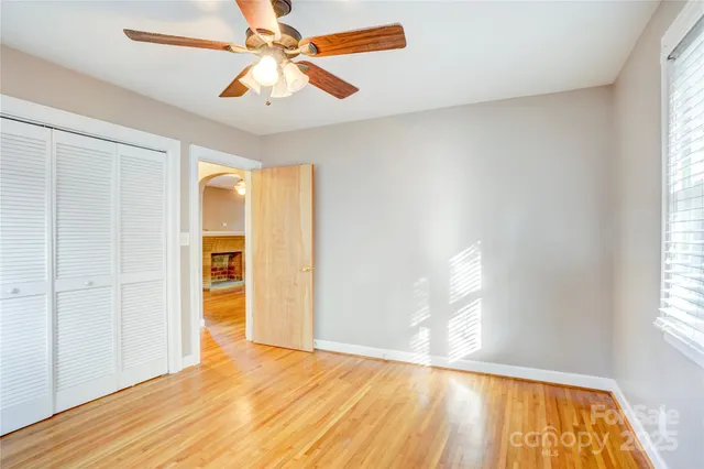 a view of empty room with wooden floor and fan