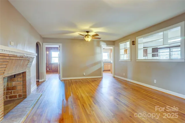 a view of an empty room with wooden floor and a fireplace