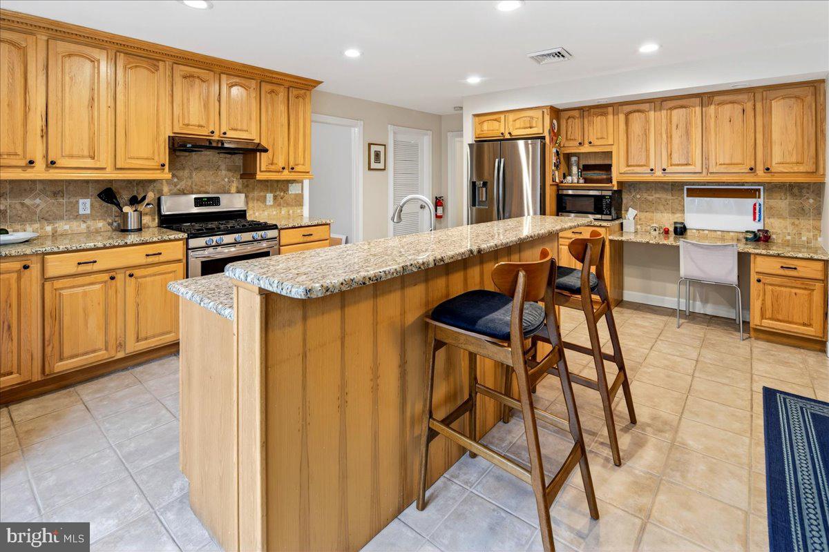 14 Baldwin Street Pennington, NJ 08534 - Photo 15 of 42 a kitchen with stainless steel appliances granite countertop a stove top oven a sink a dining table and chairs with wooden floor