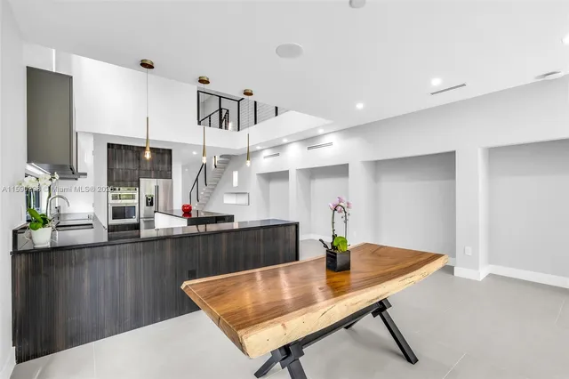 a kitchen with stainless steel appliances kitchen island granite countertop a table chairs in it and wooden floors