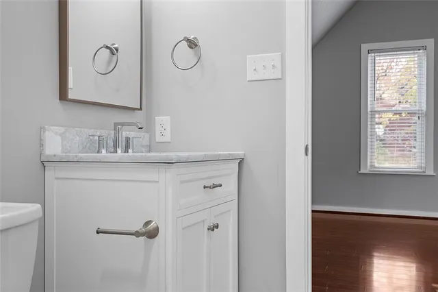 a view of an empty room with wooden floor and a ceiling fan