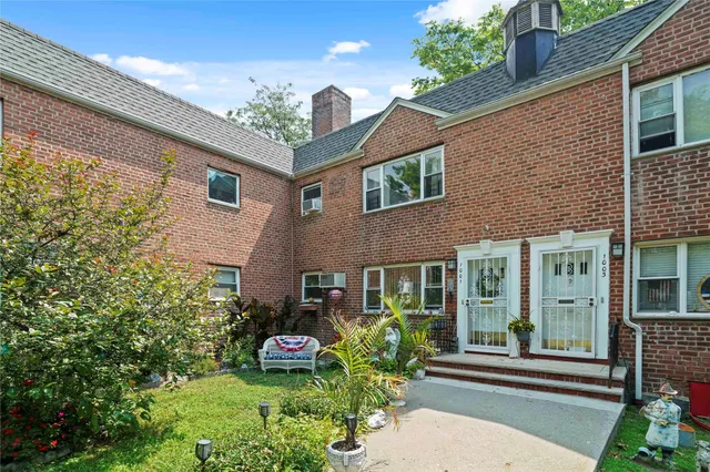 a front view of a house with a yard and potted plants