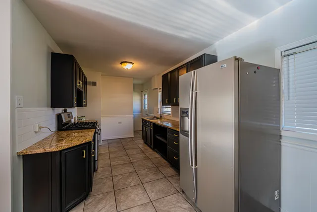 a kitchen with granite countertop a refrigerator and a stove top oven