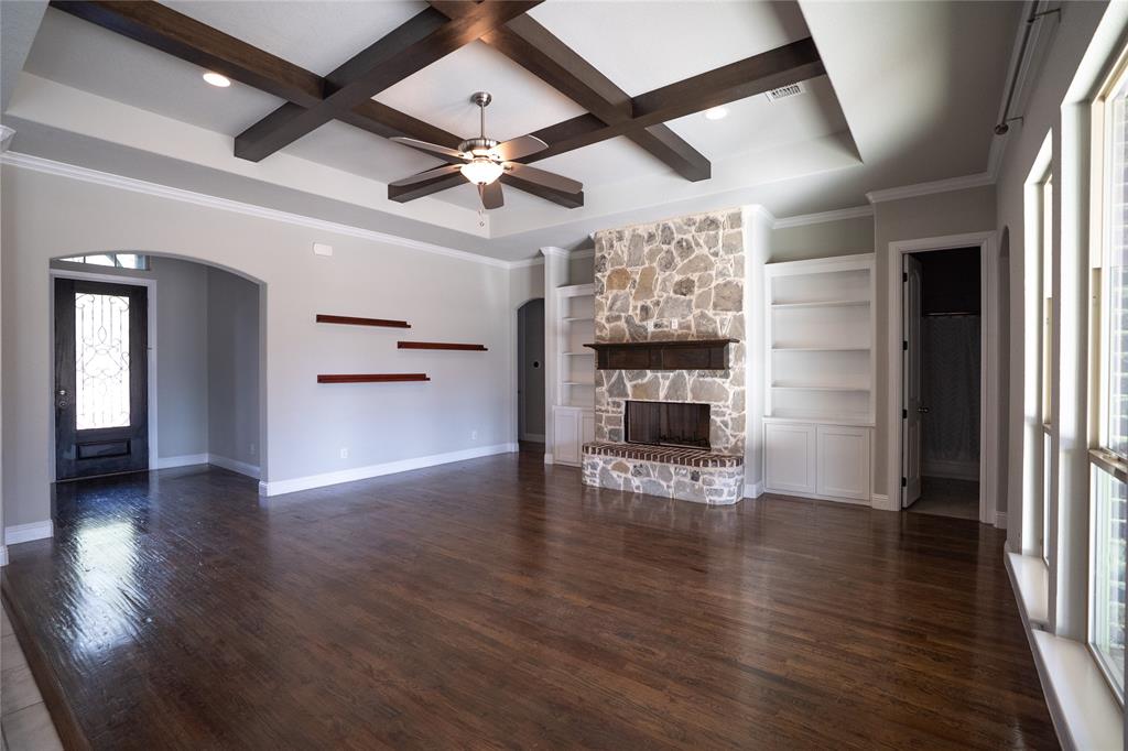 181 Fairview Court Decatur, TX 76234 - Photo 9 of 35 an empty room with wooden floor a ceiling fan a fireplace and windows