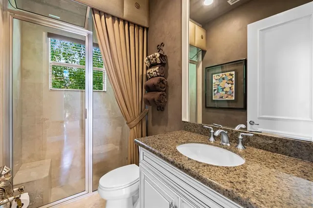 a bathroom with a granite countertop sink toilet a mirror and shower