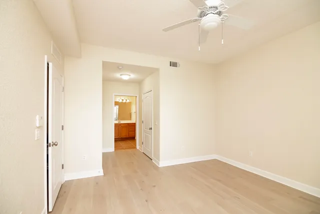 a view of a hallway with wooden floor and a bathroom