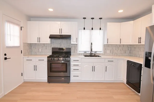 a kitchen with stainless steel appliances granite countertop a stove and white cabinets