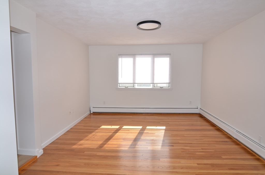 88 Cleveland Avenue, Unit 2 Everett, MA 02149 - Photo 7 of 23 an empty room with wooden floor and windows
