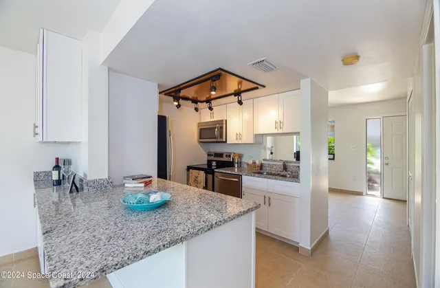 a kitchen with stainless steel appliances kitchen island granite countertop a sink cabinets and wooden floor
