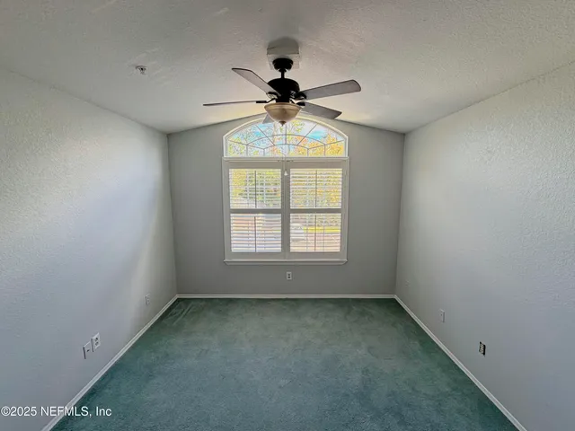 an empty room with a window and a ceiling fan