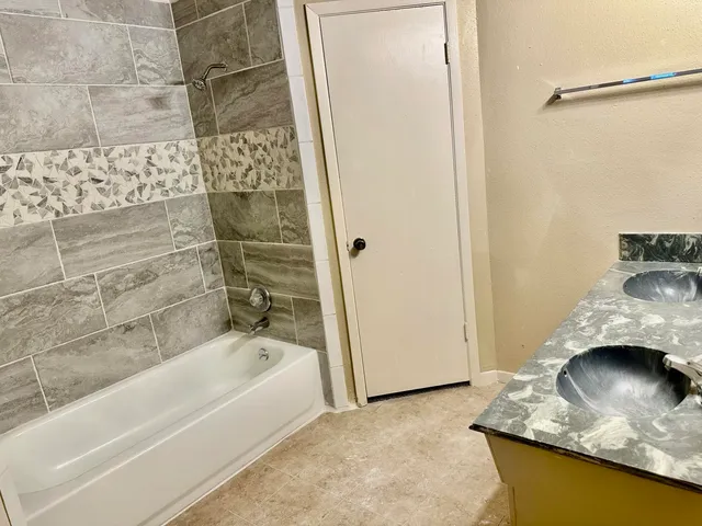 a bathroom with a granite countertop sink and a bathtub