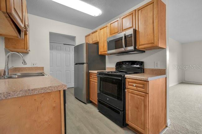 1695 Lee Road, Unit E204 Winter Park, FL 32789 - Photo 11 of 27 a kitchen with stainless steel appliances granite countertop a sink stove microwave and refrigerator