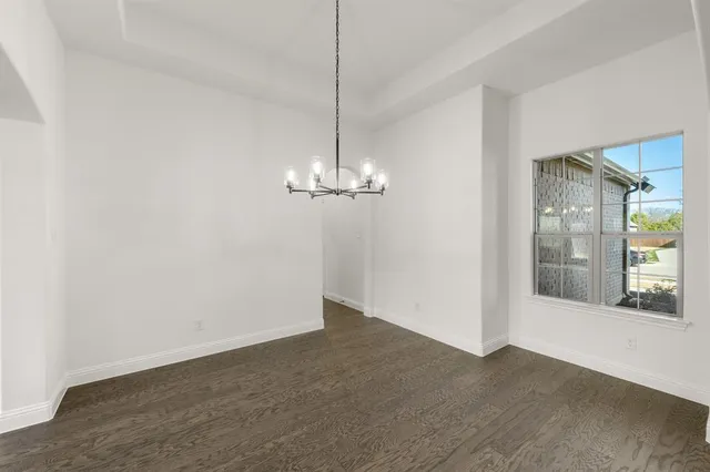 a view of empty room with wooden floor and window