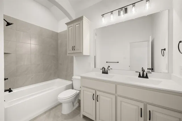 a bathroom with a toilet a sink a mirror a bathtub and vanity