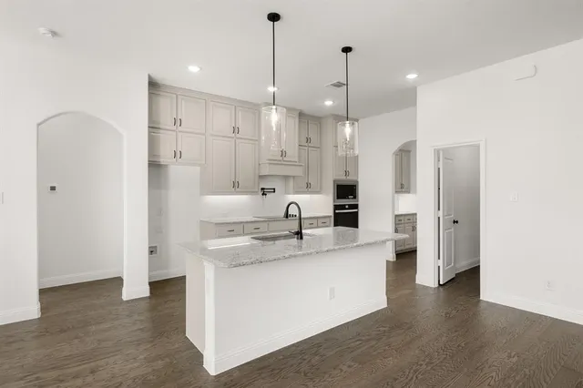 a large kitchen with stainless steel appliances kitchen island granite countertop a refrigerator and a sink