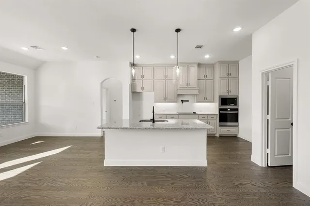 a large white kitchen with a large window and stainless steel appliances