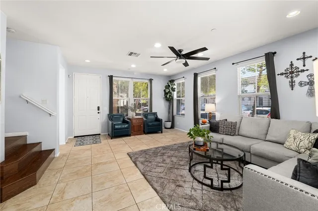 a living room with furniture a rug kitchen view and a large window