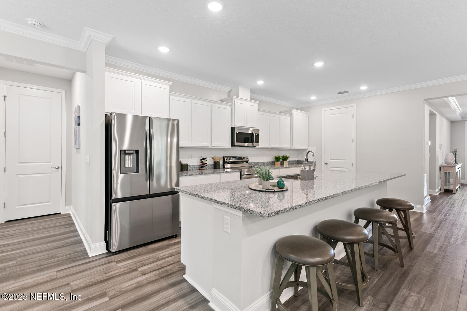 56310 Creekside Way Callahan, FL 32011 - Photo 7 of 47 a kitchen with stainless steel appliances granite countertop a refrigerator a stove a sink a dining table and chairs with wooden floor