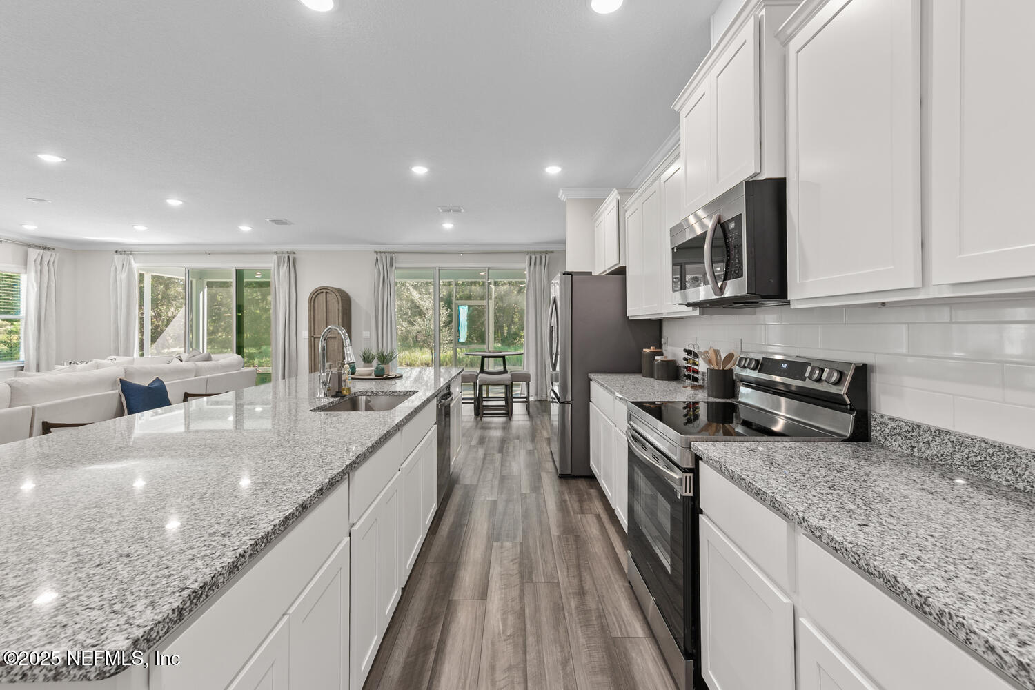 56310 Creekside Way Callahan, FL 32011 - Photo 9 of 47 a large kitchen with stainless steel appliances granite countertop a lot of counter space a sink and dishwasher a stove top oven with wooden floor