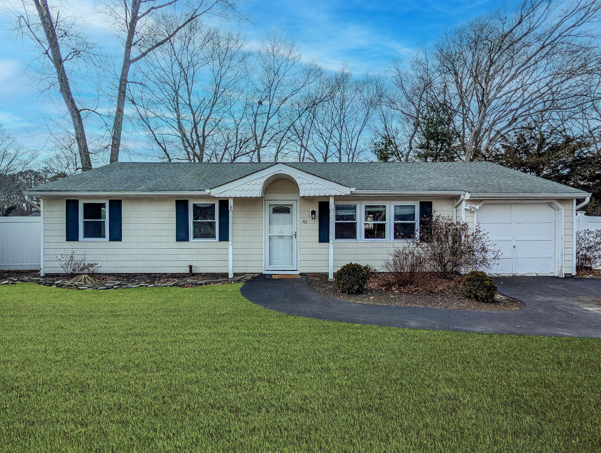 Single story home featuring aphalt driveway, a front yard, a shingled roof, and a garage